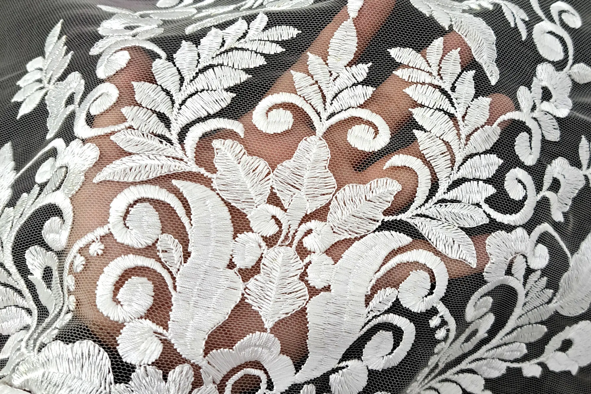 Brukat bordir putih di atas kain tile, difoto dari dekat